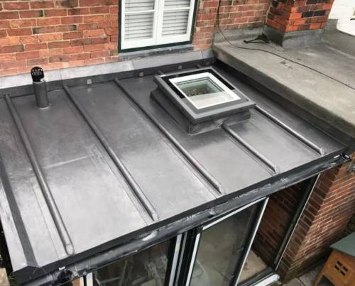 New lead-look standing-seam flat roof with a roof window, fitted over a rear extension
