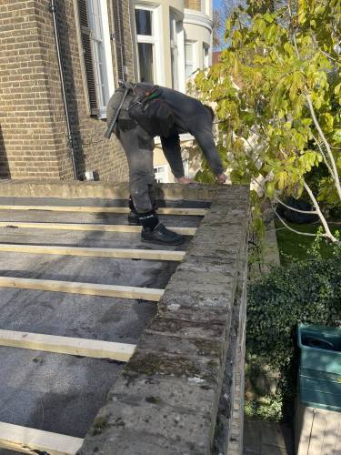 Roofer laying new timber decking ahead of a flat roof covering