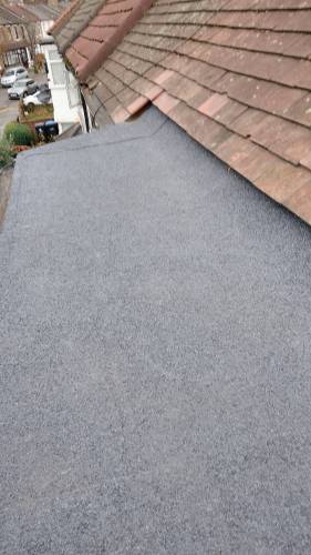 Newly completed grey flat roof covering next to an existing pitched tiled roof
