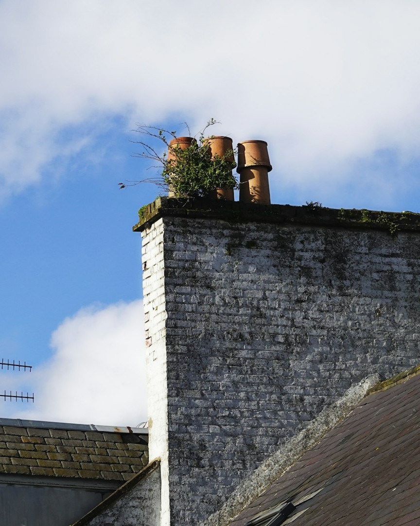 Traditional UK slate roof with terracotta chimney pots against a blue sky